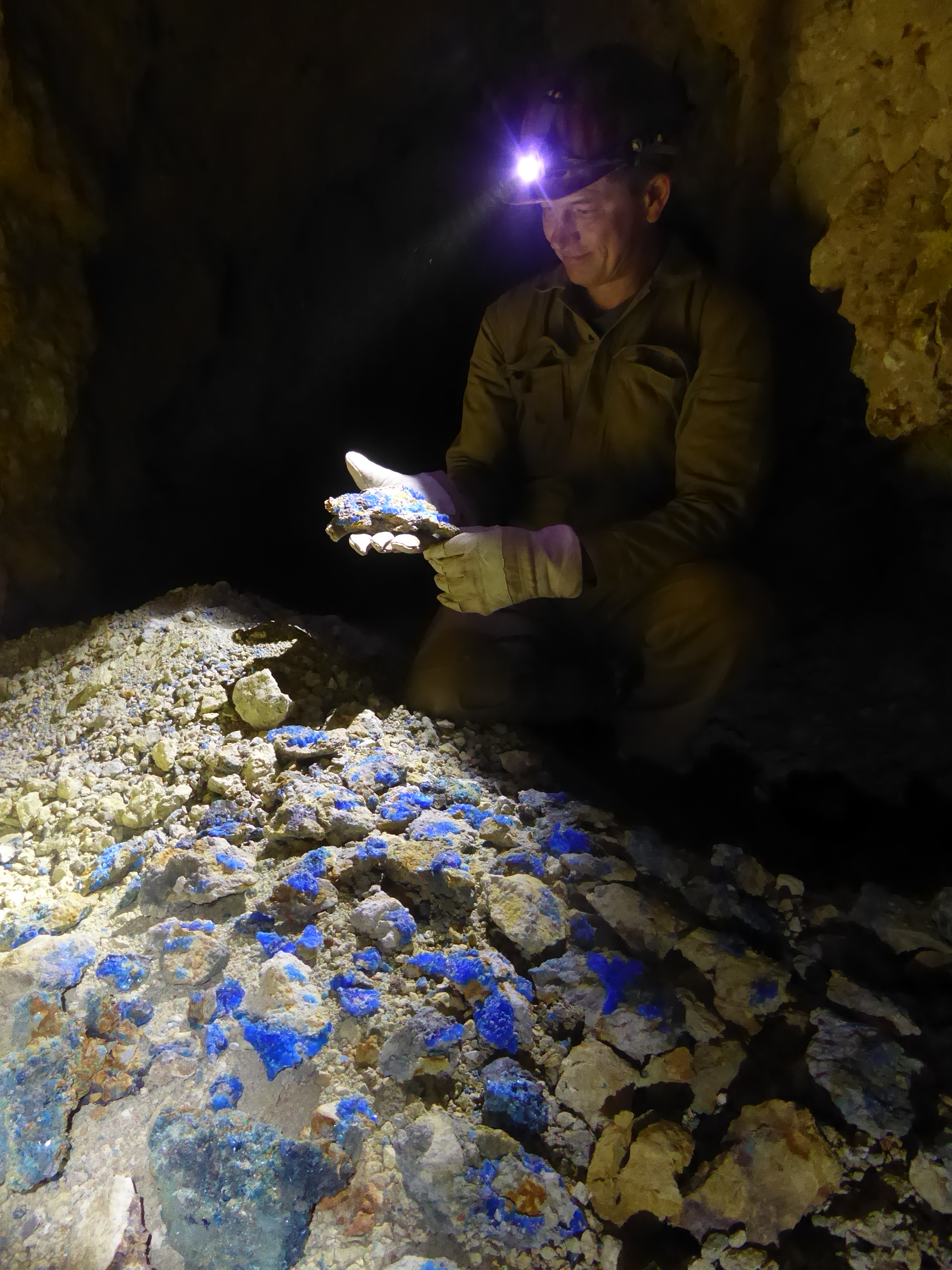 Mann in einer Höhle betrachtet Mineralien